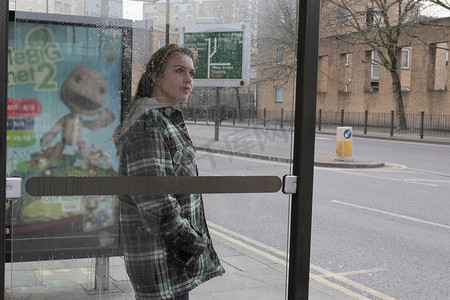 雨中的公交车候车处的年轻女子