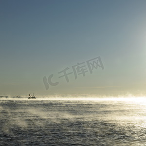 黎明的阳光薄雾中海景和渔船在地平线上