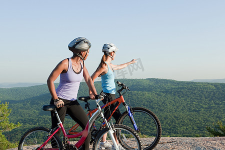 紫色场景摄影照片_两个骑自行车的女性乡村场景