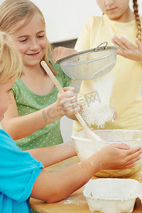 孩子们烘焙把面粉筛进搅拌碗里