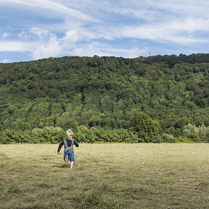 德国北莱茵威斯特伐利亚州韦斯特法利卡门男孩在田野里奔跑的背影