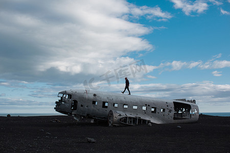 中年男子走在飞机残骸上的侧视冰岛火山景观