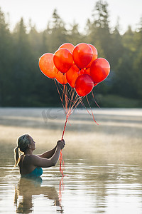 水中女子手持一串红色气球