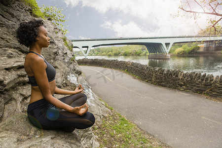 一名妇女盘腿坐在岩石上冥想