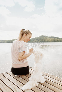 芬兰奥里维西一名女子在湖码头上抚摸科顿·德·图利尔狗