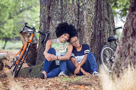 卡通轮滑儿童摄影照片_成熟的女人和儿子坐在公园的树上