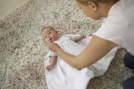 童装上新摄影照片_第二步母亲让躺在毯子上的男婴做准备