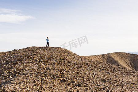 美国加利福尼亚州奥兰查沙漠砾石山顶上的男孩