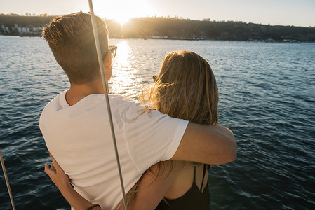 美国加利福尼亚州圣地亚哥湾一对情侣在帆船上欣赏日落