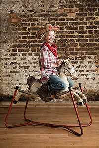 年轻女孩打扮成牛仔骑着摇摆的马