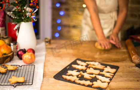 圣诞摄影照片_在厨房柜台前压平圣诞饼干糕点的妇女的中段