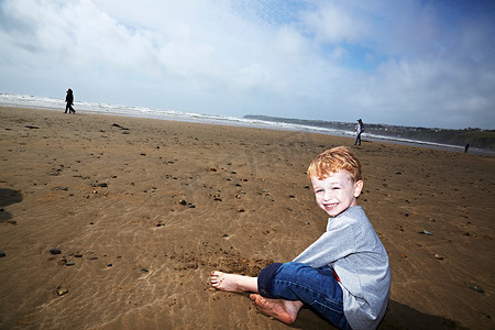 坐在海滩上微笑的男孩
