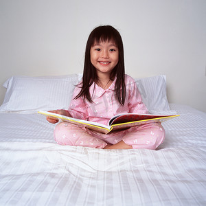 年轻女孩抱着书躺在床上