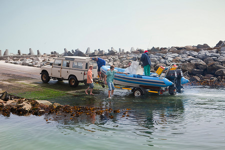 一小群人用小艇登上港口的拖车