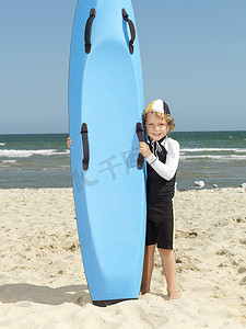澳大利亚墨尔本阿尔托纳海滩冲浪板旁的可爱男孩儿童冲浪救生员肖像