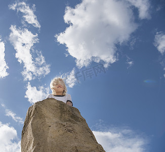 站在岩石顶上的男孩看向别处