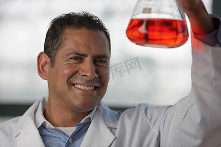 化学思考摄影照片_成熟的科学家在容量瓶中观察液体