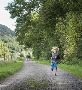 德国北莱茵威斯特伐利亚波塔韦斯特法利察一家人在乡间公路上奔跑的男孩