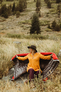 美国加利福尼亚州红杉国家公园矿物王坐在乡村背景下裹着睡袋的女人