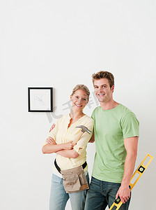 纯色装修摄影照片_年轻夫妇手持工具画在墙上