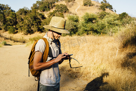 美国加利福尼亚州马里布峡谷徒步旅行者低头看智能手机