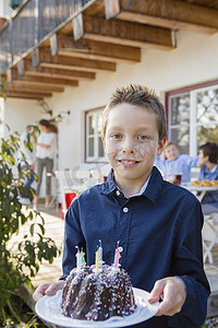 男孩在露台上拿着生日蛋糕的肖像