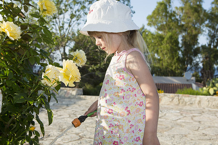 玫瑰家族摄影照片_戴着太阳帽的女孩浇水玫瑰