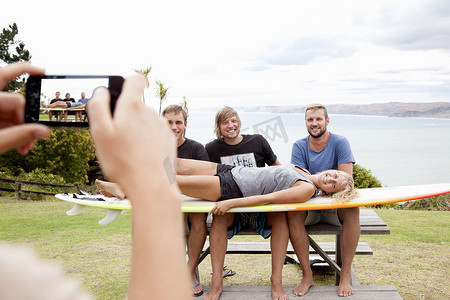 年轻女子用智能手机为冲浪朋友拍照