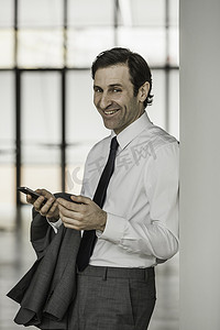成熟商人的肖像使用智能手机微笑着