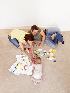 年轻的家庭在地板上展示颜色样品
