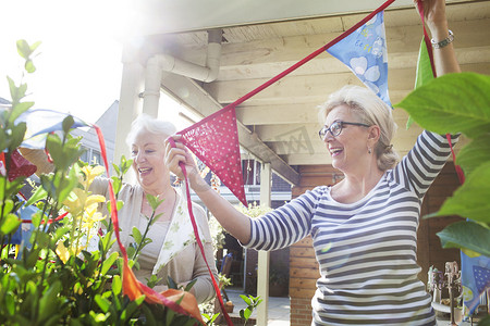 追逐摄影照片_花园里的两个女人挂着五颜六色的彩旗