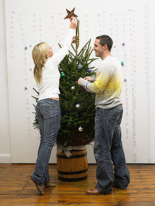 冬装饰摄影照片_装饰圣诞树的中年夫妇
