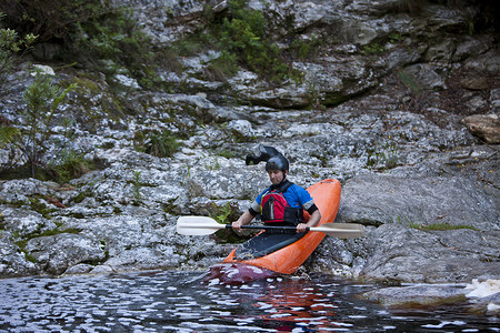 中年女性运动摄影照片_一名中年男子将皮划艇从水边移入河中
