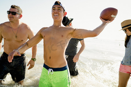 美国加利福尼亚州纽波特海滩四位成年朋友在海上踢美式足球