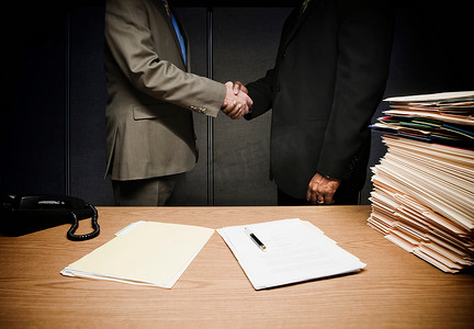 两位商人在办公桌前握手