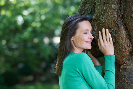 微笑的女人拥抱着树