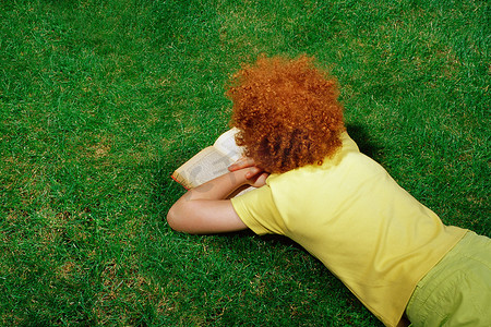 黄狮鱼摄影照片_躺在草地上看书的女孩
