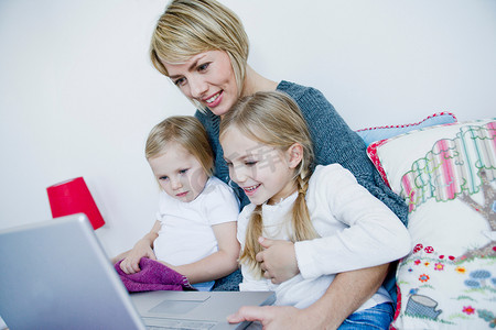 航空母摄影照片_母亲和两个女孩在看笔记本电脑
