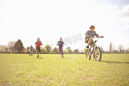 跑步运动场摄影照片_一群男孩在操场上跑步和骑自行车