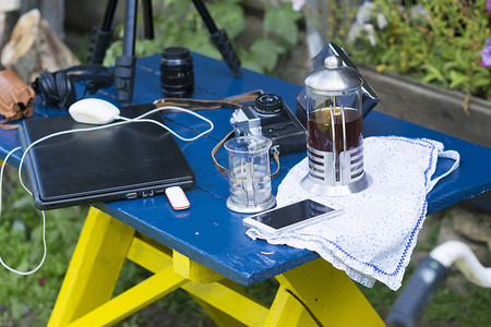花园里的桌子上有照相设备笔记本电脑和咖啡桌