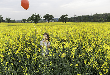 站在黄色花田里手持红色气球的男孩肖像