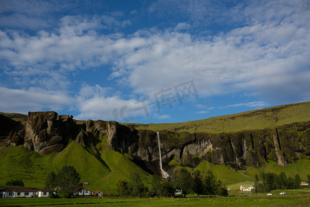 偏远的村庄瀑布流过郁郁葱葱的绿色山脉冰岛