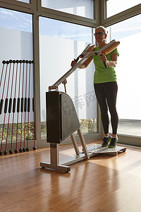 健身器摄影照片_成年女性在健身房健身器上做举重练习