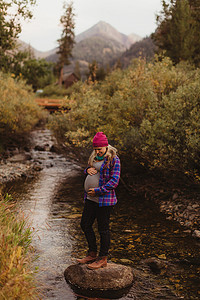 孕妇站在小溪的岩石上抱着肚子矿物之王美国加利福尼亚州红杉国家公园