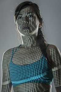 灰色背景下的中年妇女肖像穿着运动服网格投射到面部和身体上