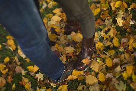 站在秋叶上的中年夫妇的腿和脚