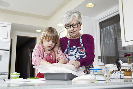 女孩和奶奶在厨房柜台前准备防油纸