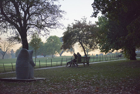 秋天公园里坐在公园长椅上的老妇人和女儿的剪影
