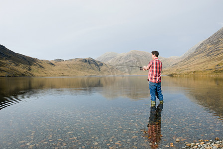 逃生竿摄影照片_一名男子在湖里钓鱼
