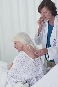 女医生用听诊器听高龄女患者回诊